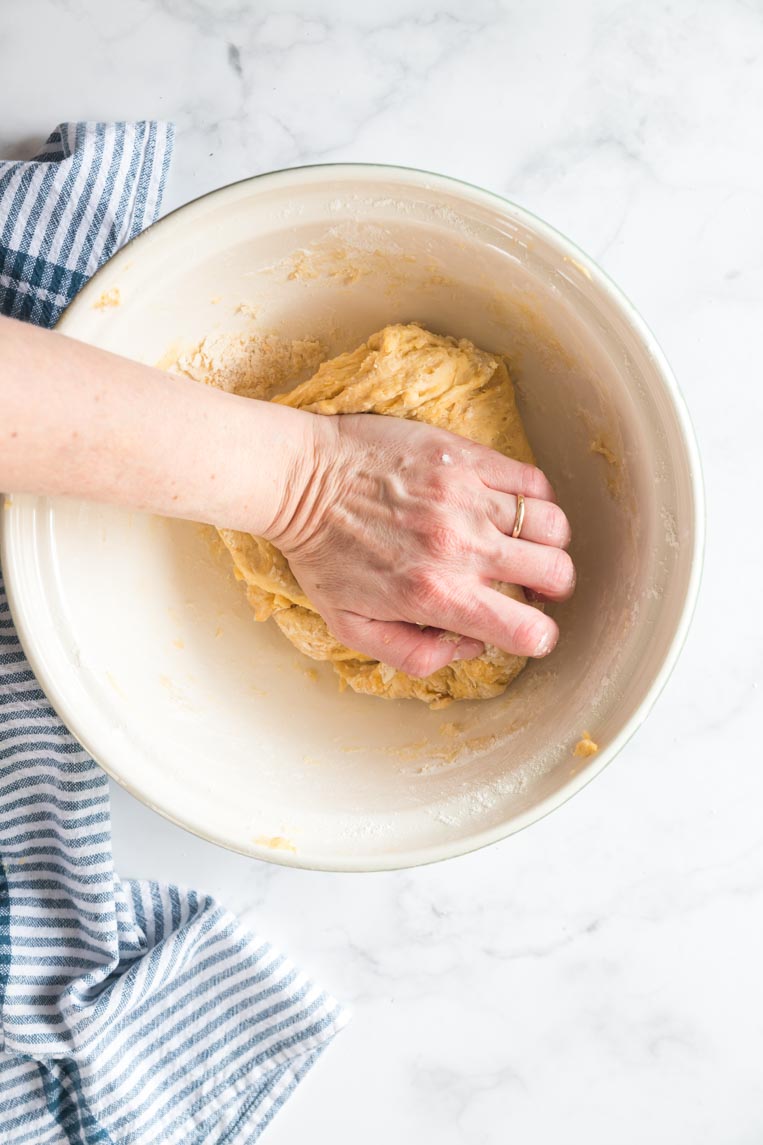 a hand kneading dough in a bowl 