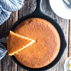 a skillet of cornbread with a slice being lifted out