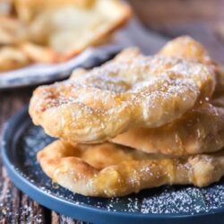 a stack of Indian fry bread on a plate with honey and powdered sugar