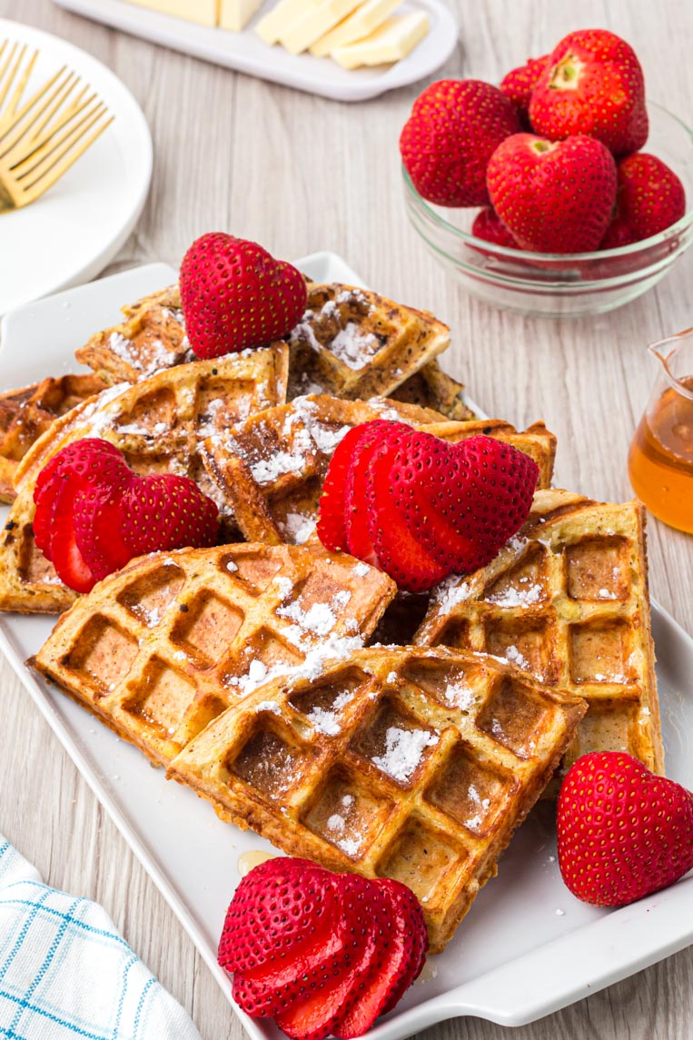 a plate of french toast waffles with strawberries on a plate. 