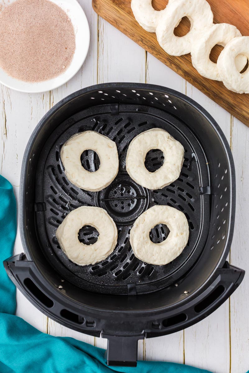 Four biscuit donuts in the basket of an air fryer. 