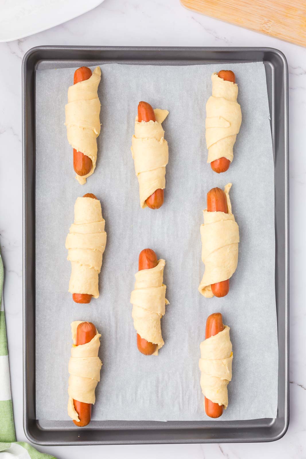 a pan of rolled hot dog snacks ready to bake. 