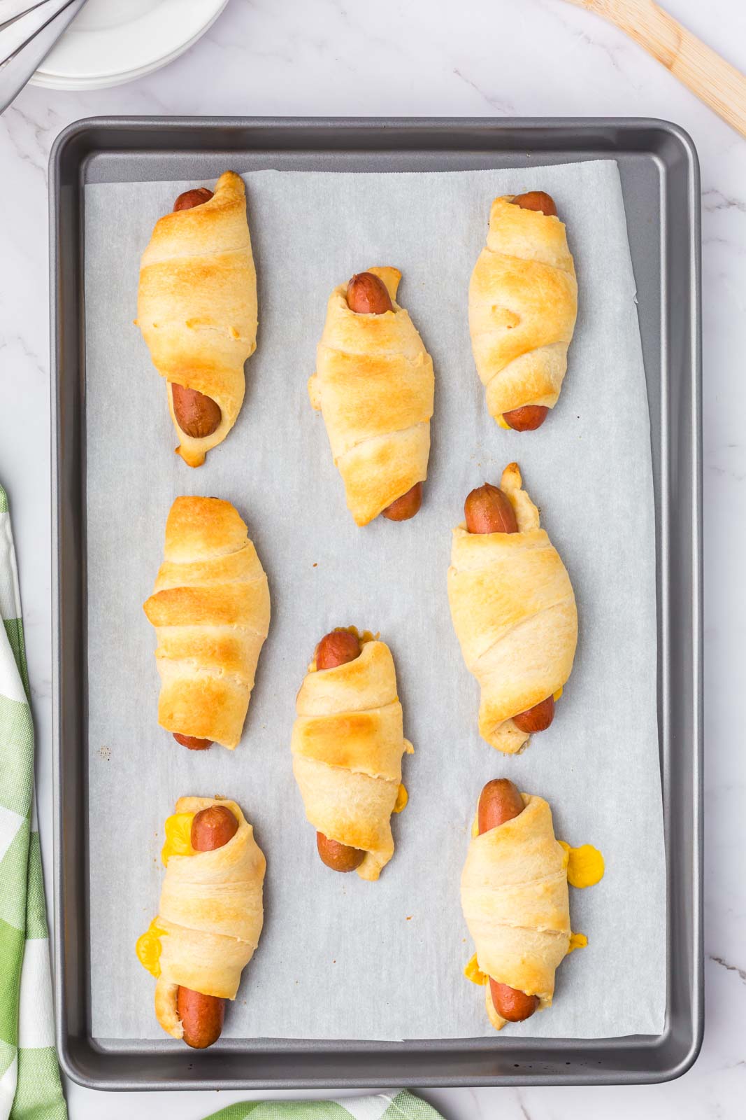 a pan of crescent roll dogs baked on a cookie sheet