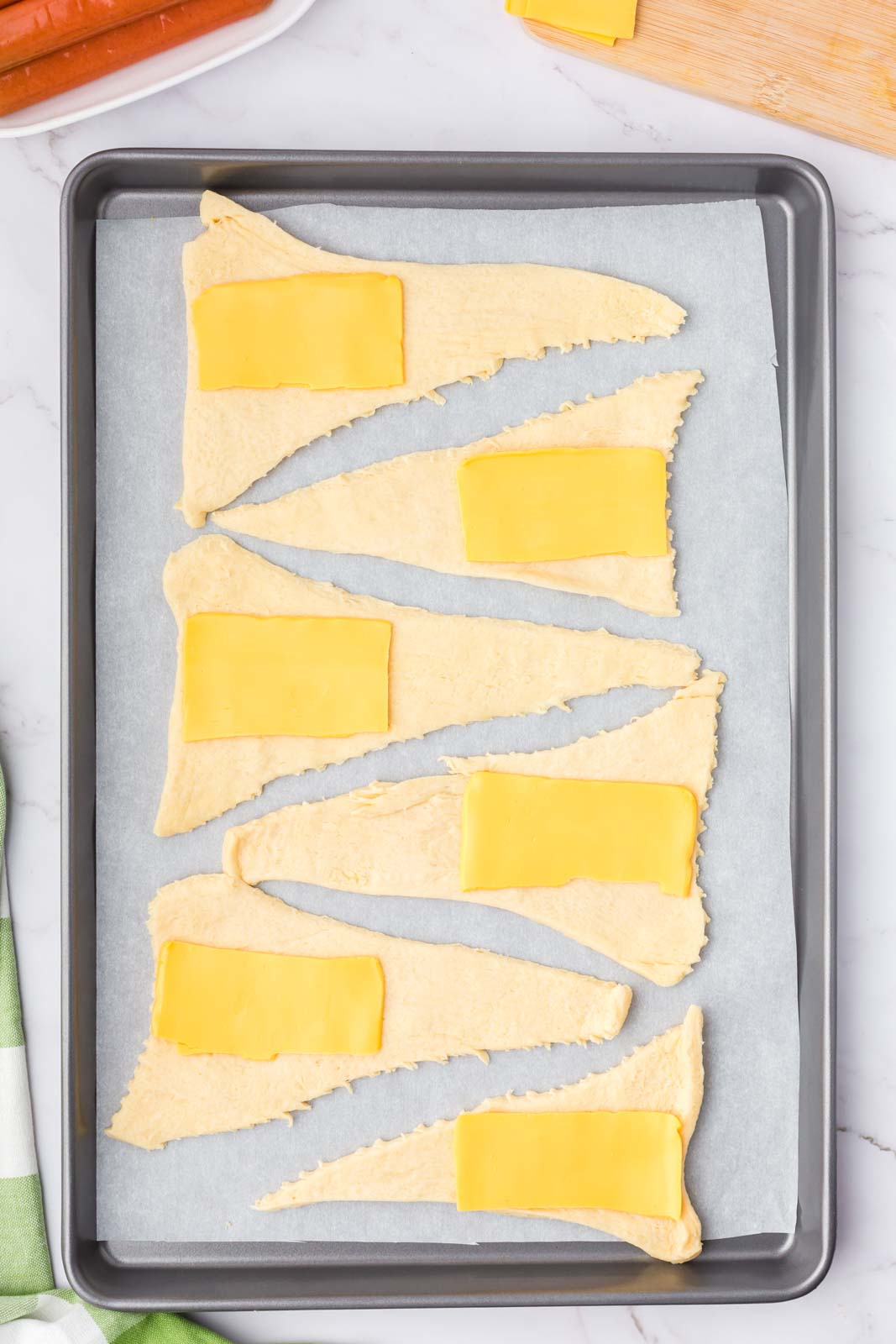 a cookie sheet with triangles of crescent dough with cheese squares on them