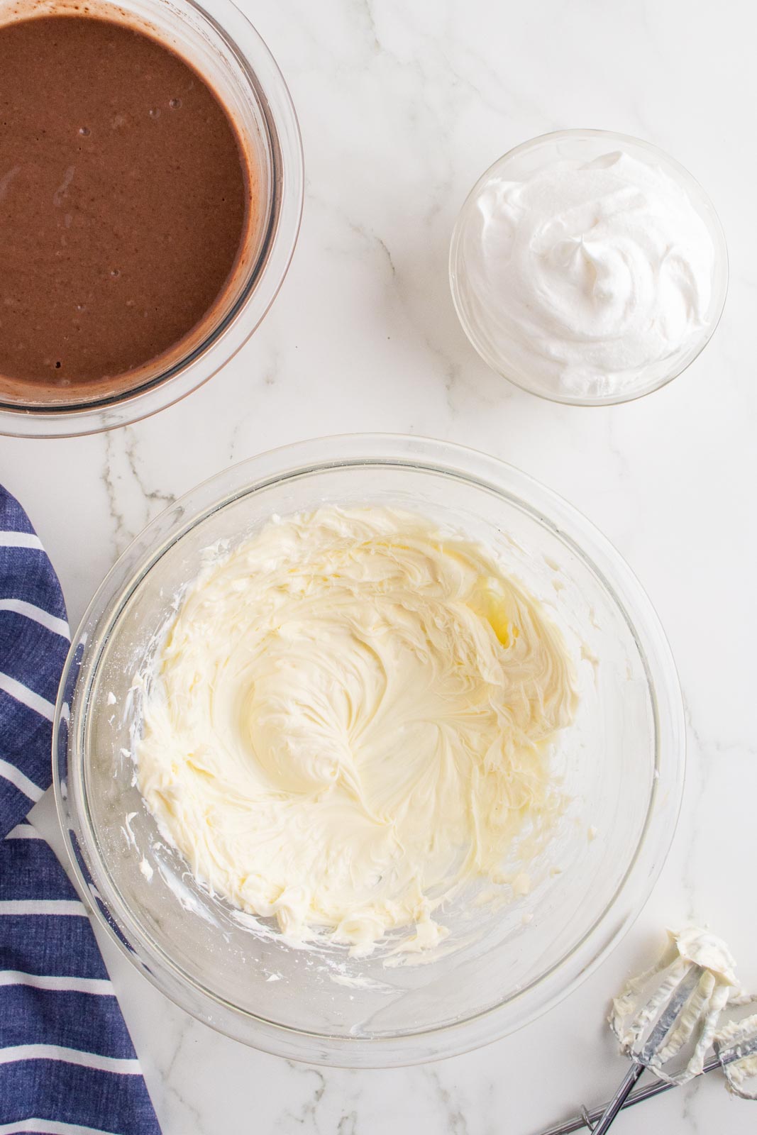 Beating together cream cheese and powdered sugar in a mixing bowl.